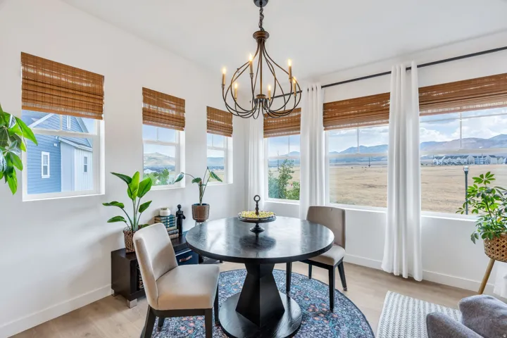 Dining area featuring multiple windows, a wrought iron chandelier, light wood-finish flooring, and natural woven shades
