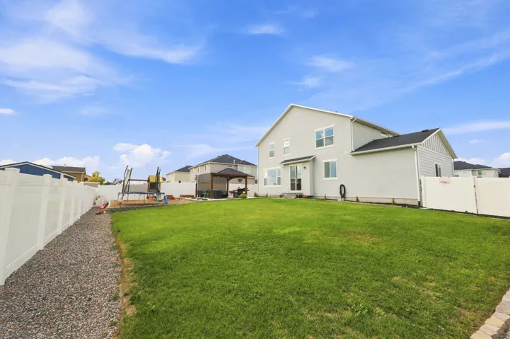 Expansive backyard featuring a large lawn area, full perimeter fencing, and a built-in gazebo