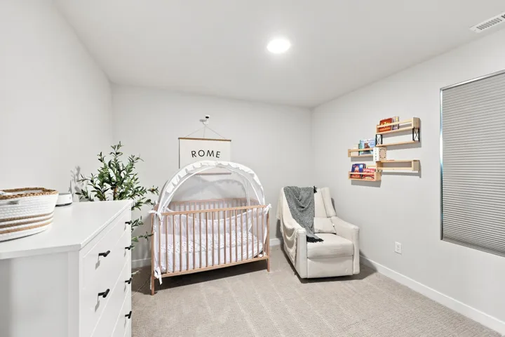 Recessed lighting, wall-to-wall carpeting, and a window with cellular shades