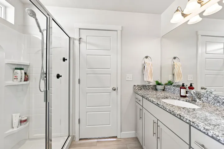 Walk-in shower with clear glass enclosure and built-in shelving