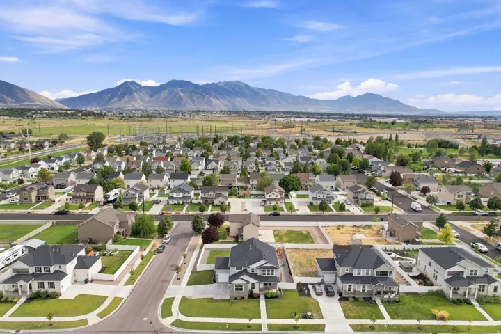 Residential neighborhood with established homes and undeveloped lots, set against a backdrop of distant mountains and open fields