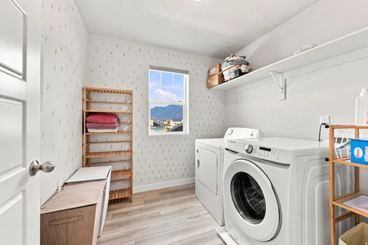 Wood-finish flooring with a side-by-side washer and dryer, and wall-mounted shelving