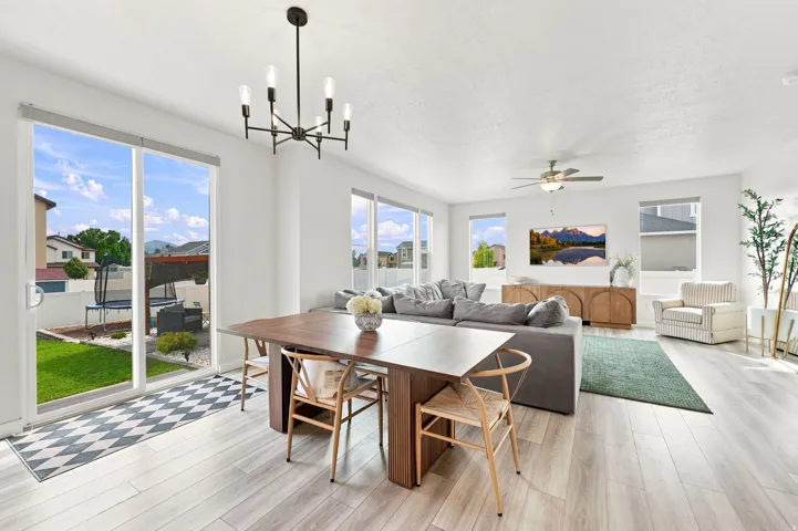 Open-concept living space featuring wood-finish flooring, multiple windows, a ceiling fan, and recessed lighting