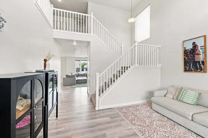 Two-story entryway featuring wood-finish flooring, white staircase with balusters, and a high ceiling