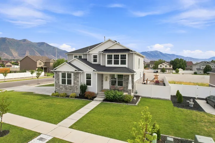 Two-story residence with a stone and siding exterior, front-facing gables, a covered entry, and a paved driveway