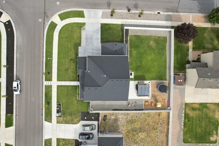 Paved street with curving sidewalks, concrete driveway, and an expansive lawn