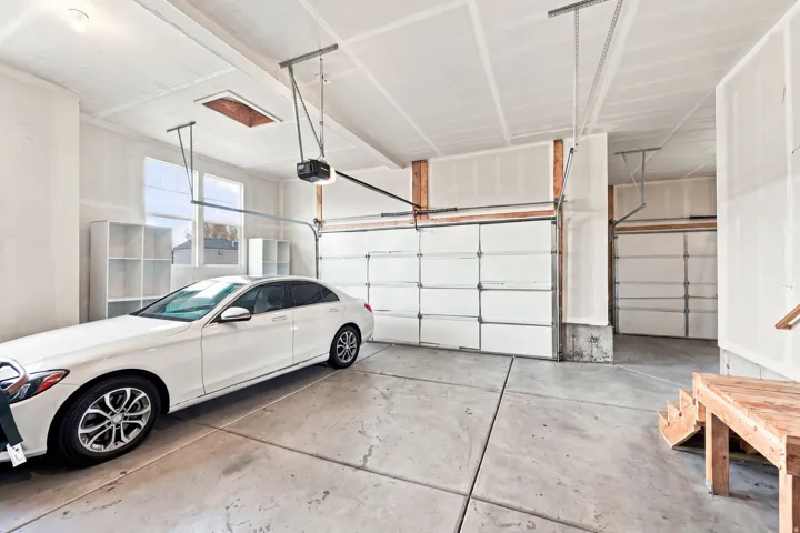 Spacious garage featuring two overhead doors, a concrete floor, and multiple windows