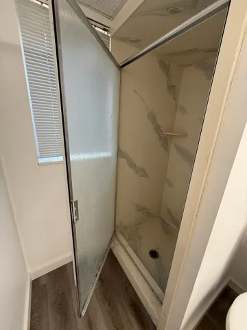 Shower enclosure with patterned wall panels, integrated shelf, and a frosted glass door