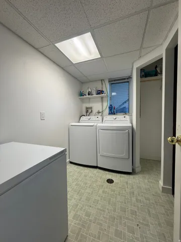 Utility room featuring patterned flooring, built-in shelving, and a drop ceiling with integrated lighting