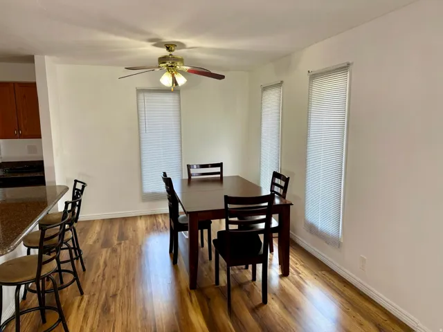 Wood-finish flooring throughout, bright white walls, and a ceiling fan with integrated lighting
