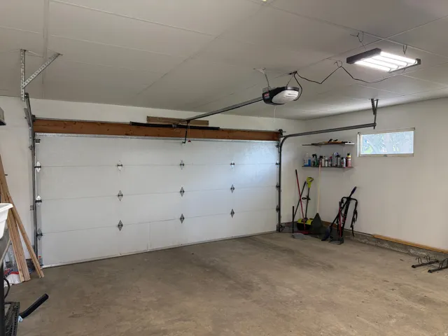 Spacious garage with a single overhead door, concrete flooring, and a single window