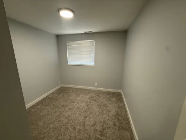 Neutral-toned walls, plush carpeting, and a window with blinds