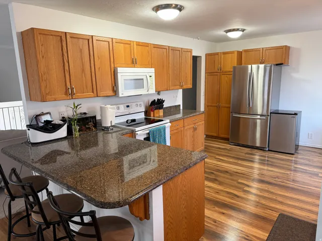 Wood-finish flooring throughout, complemented by wood cabinetry and dark speckled countertops