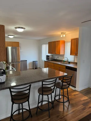 Kitchen with wood-finish flooring, granite-style countertops, wood cabinetry, and stainless steel appliances