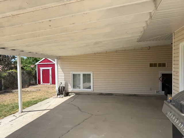 Covered patio featuring a concrete slab and a red storage shed