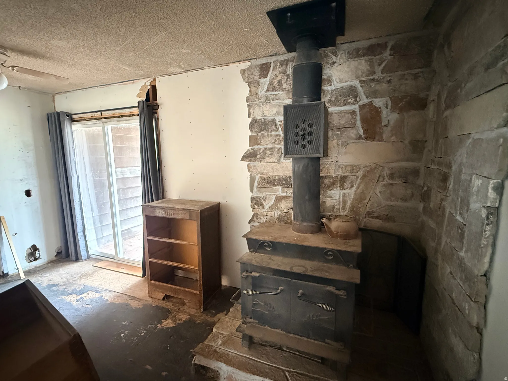 Stone-clad wall with a prominent wood-burning stove and a sliding glass door
