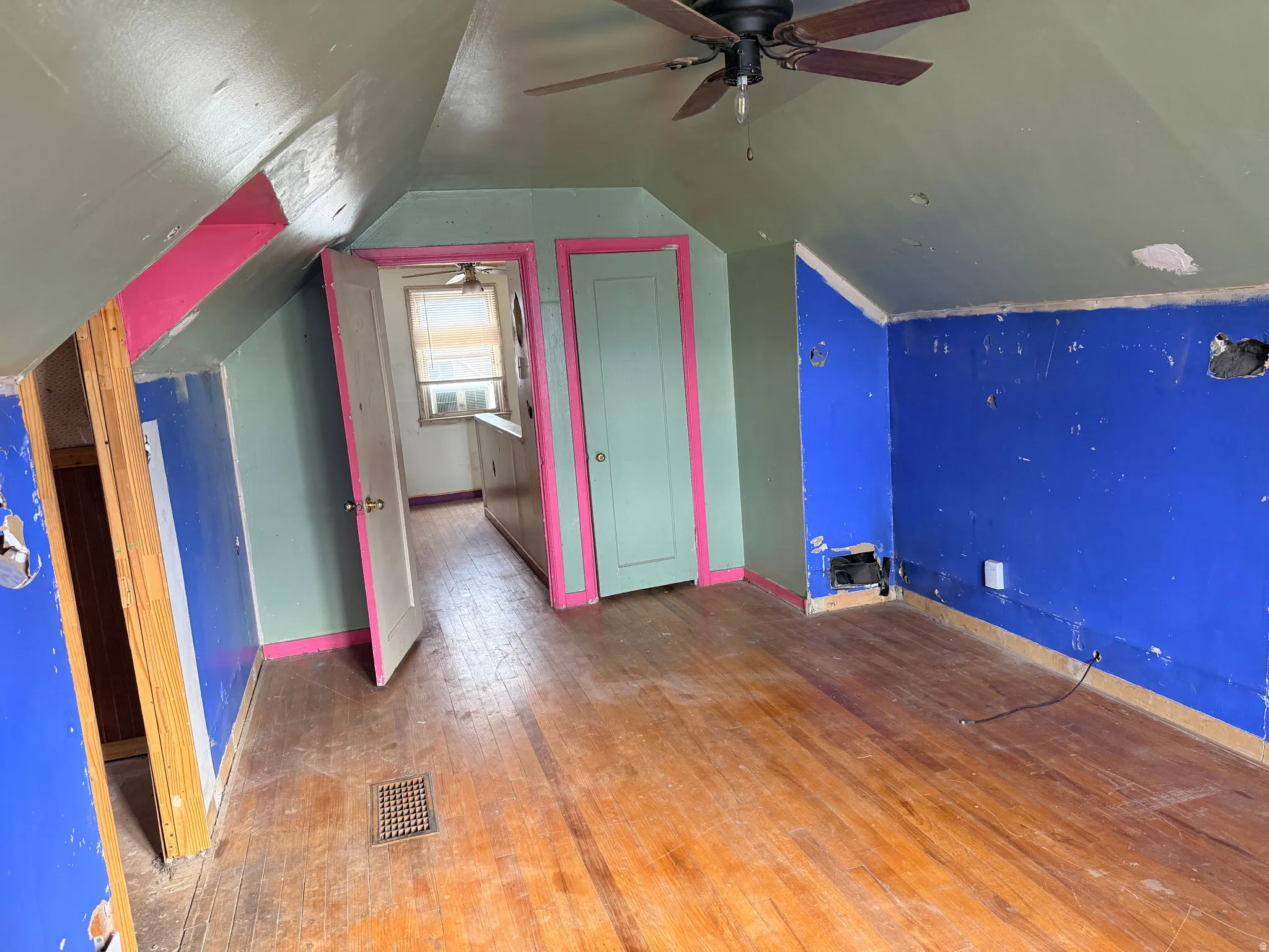 Wood-finish flooring with a ceiling fan and sloped ceilings