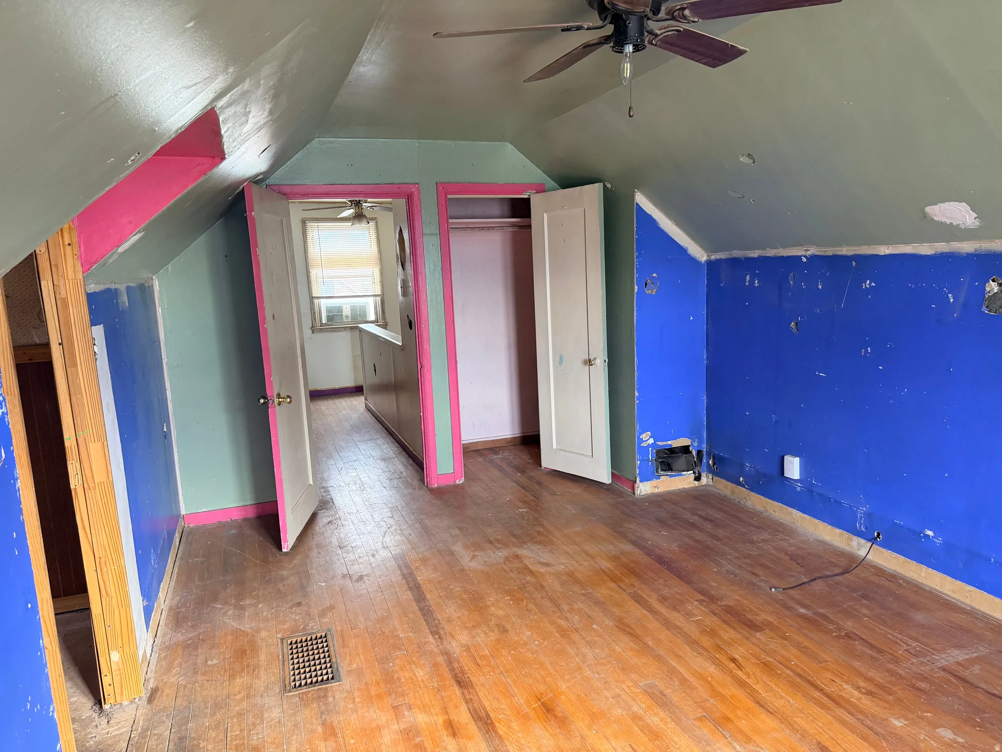 Sloped ceilings, hardwood flooring, ceiling fan, and built-in closet with shelving