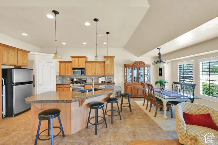 Spacious kitchen with a breakfast bar, recessed lighting, wood cabinetry, and stainless steel appliances