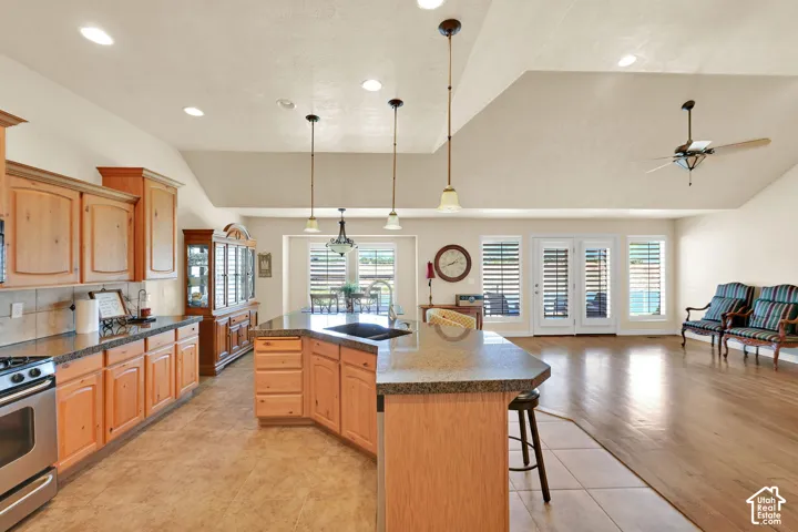 Vaulted ceilings with recessed lighting, wood-finish cabinetry, built-in stainless steel oven, stone countertops, and double glass paneled doors