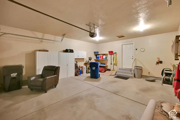 Concrete flooring, built-in overhead lighting, white entry door with steps, built-in shelving, white storage cabinetry