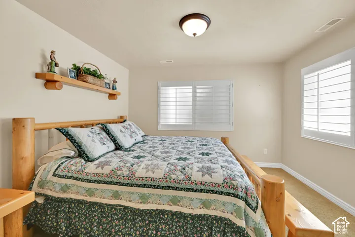 Recessed lighting, warm neutral wall tones, two windows with white plantation shutters, built-in wooden shelving, and carpeted flooring