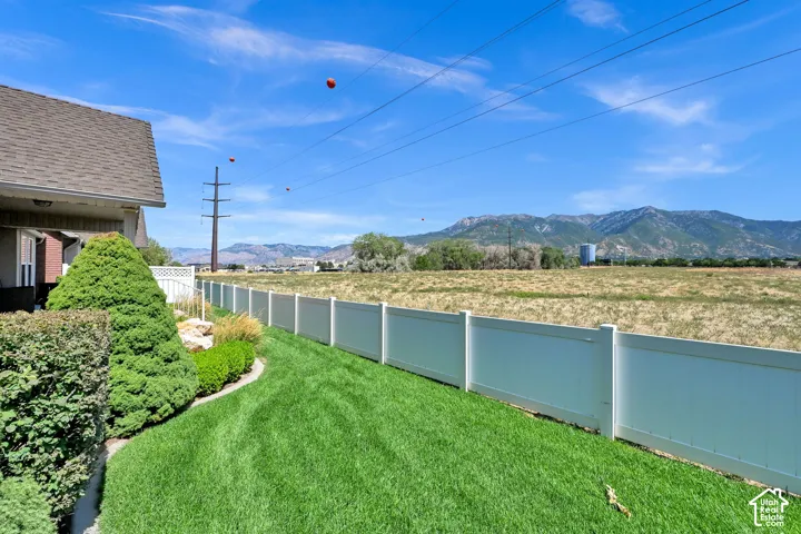 Manicured lawn, white privacy fence, mature landscaping, and mountain backdrop