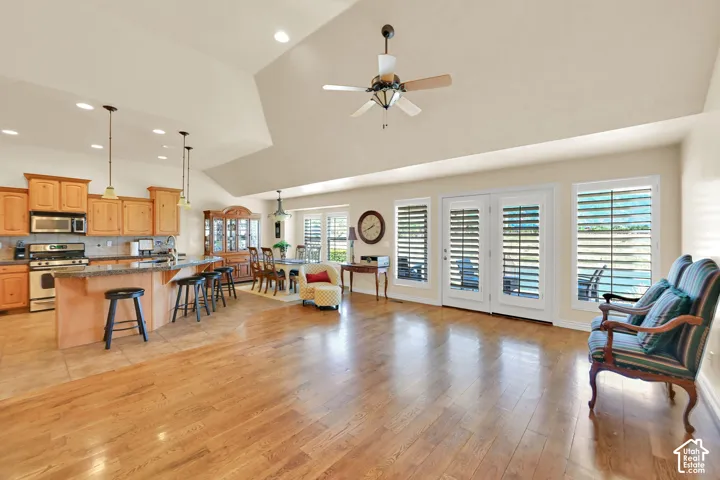 Vaulted ceilings, wood-finish flooring, recessed lighting, ceiling fan, and white plantation shutters