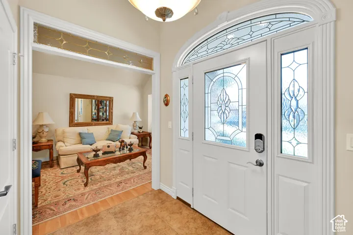 Entryway featuring a white paneled door with decorative glass inserts, an arched transom window, and a sidelight