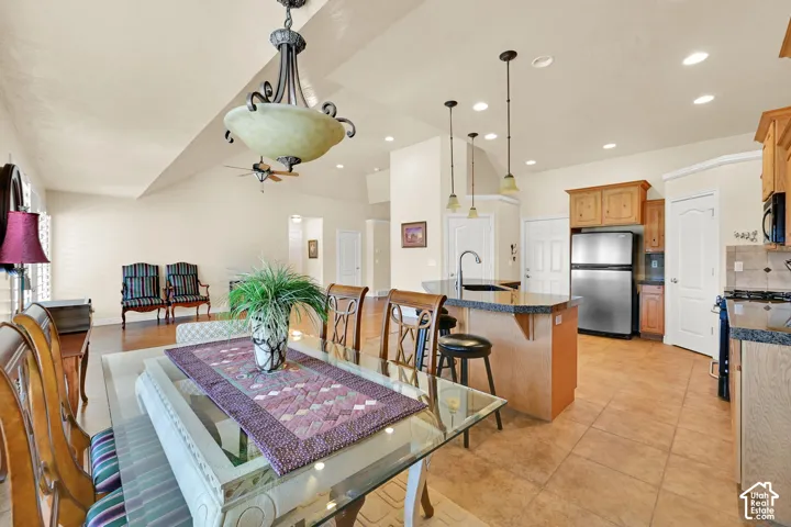 Vaulted ceiling with a ceiling fan, recessed lighting, tile flooring, wood-finish cabinetry, and stainless steel appliances