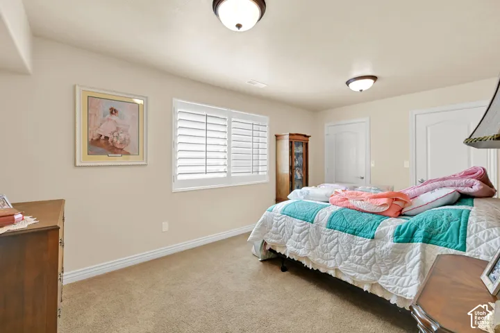 Carpeted flooring, white interior doors, wall-mounted light fixtures, and window with plantation shutters
