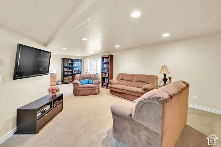 Recessed lighting illuminates this carpeted room, featuring a built-in media console, wall-mounted television, and integrated shelving