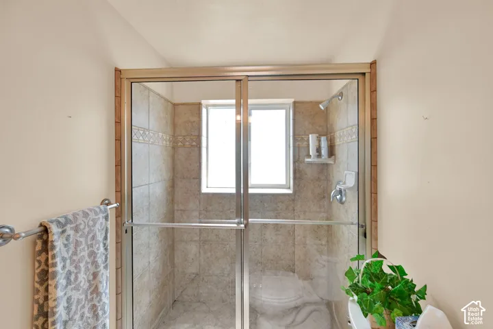 Tiled shower enclosure with sliding glass doors, built-in window, and integrated shower head