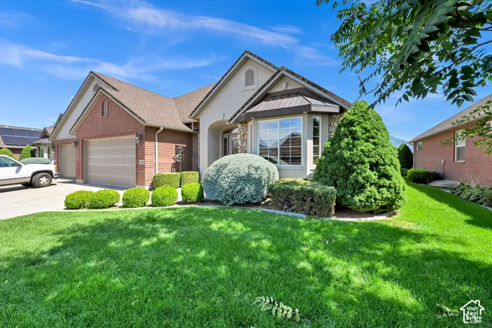 Brick and stone exterior with a bay window, a multi-car garage, and landscaped front yard