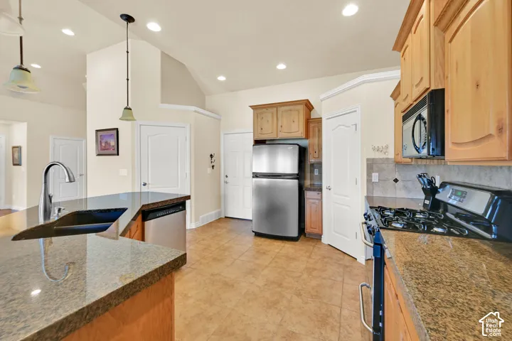 Kitchen featuring granite countertops, wood cabinetry, stainless steel appliances, and tile flooring