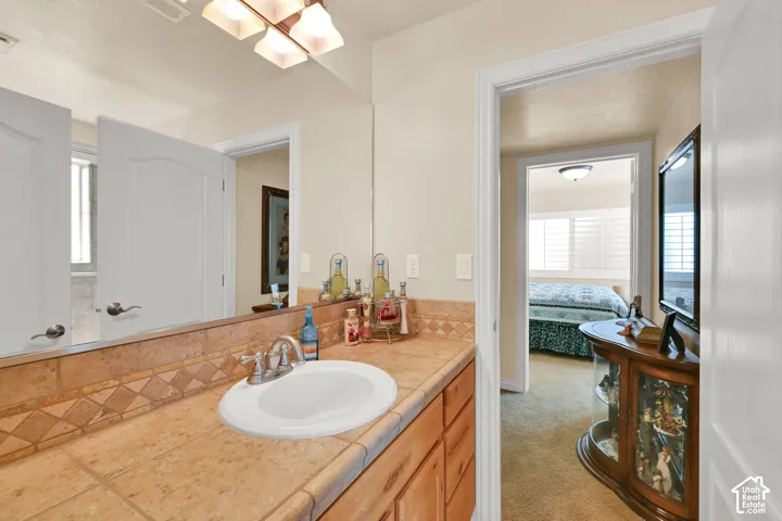 Vanity with a single basin sink, tile countertop, and wood-finish cabinetry