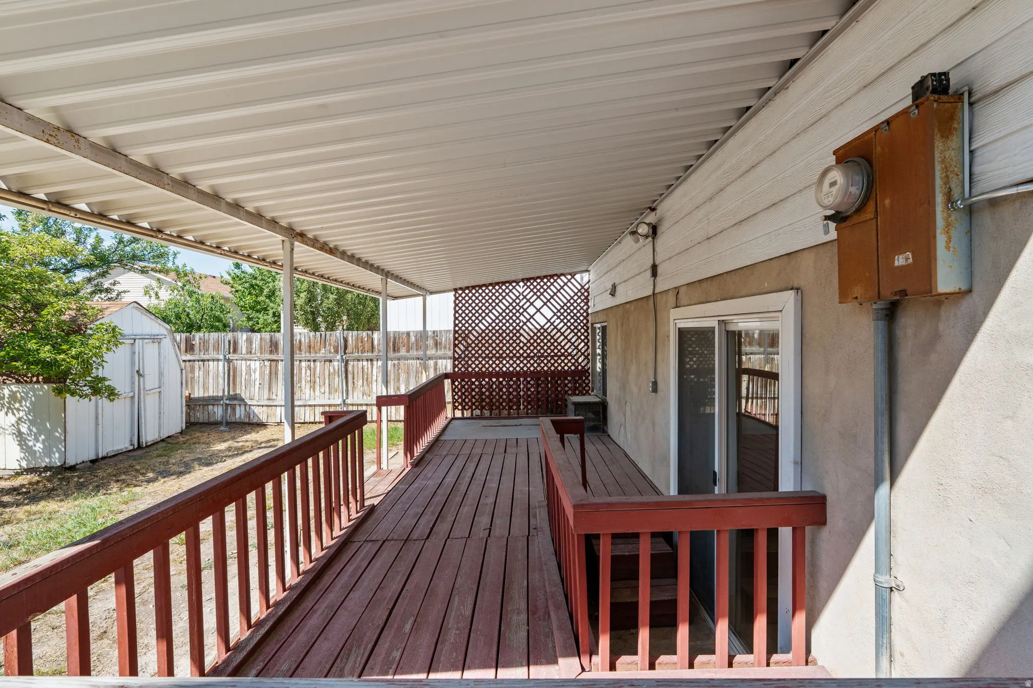 Covered wood deck with red railings, providing outdoor living space