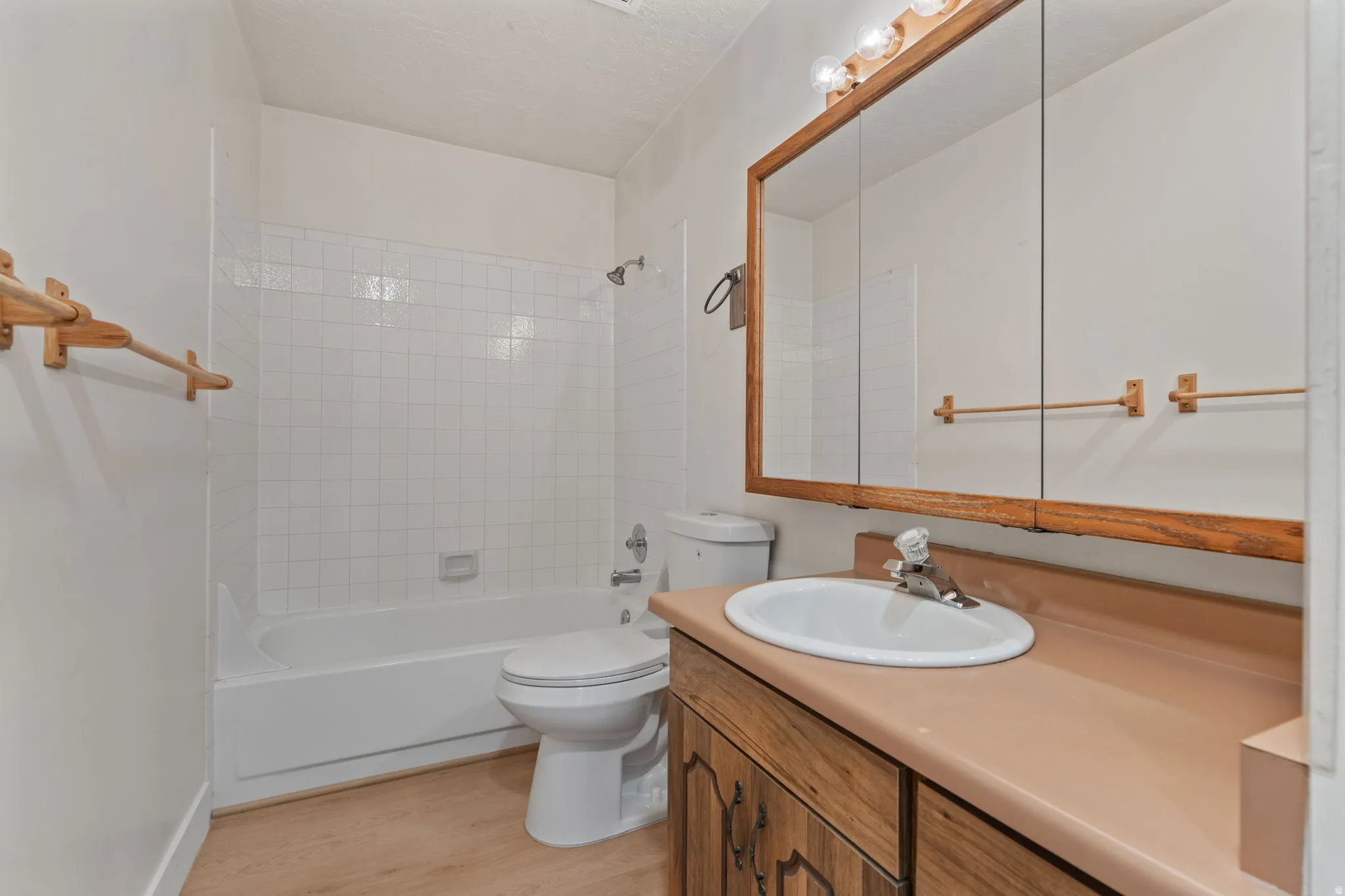 Bathroom featuring a built-in vanity with wood-finish cabinetry, an integrated sink, and a framed medicine cabinet with overhead lighting