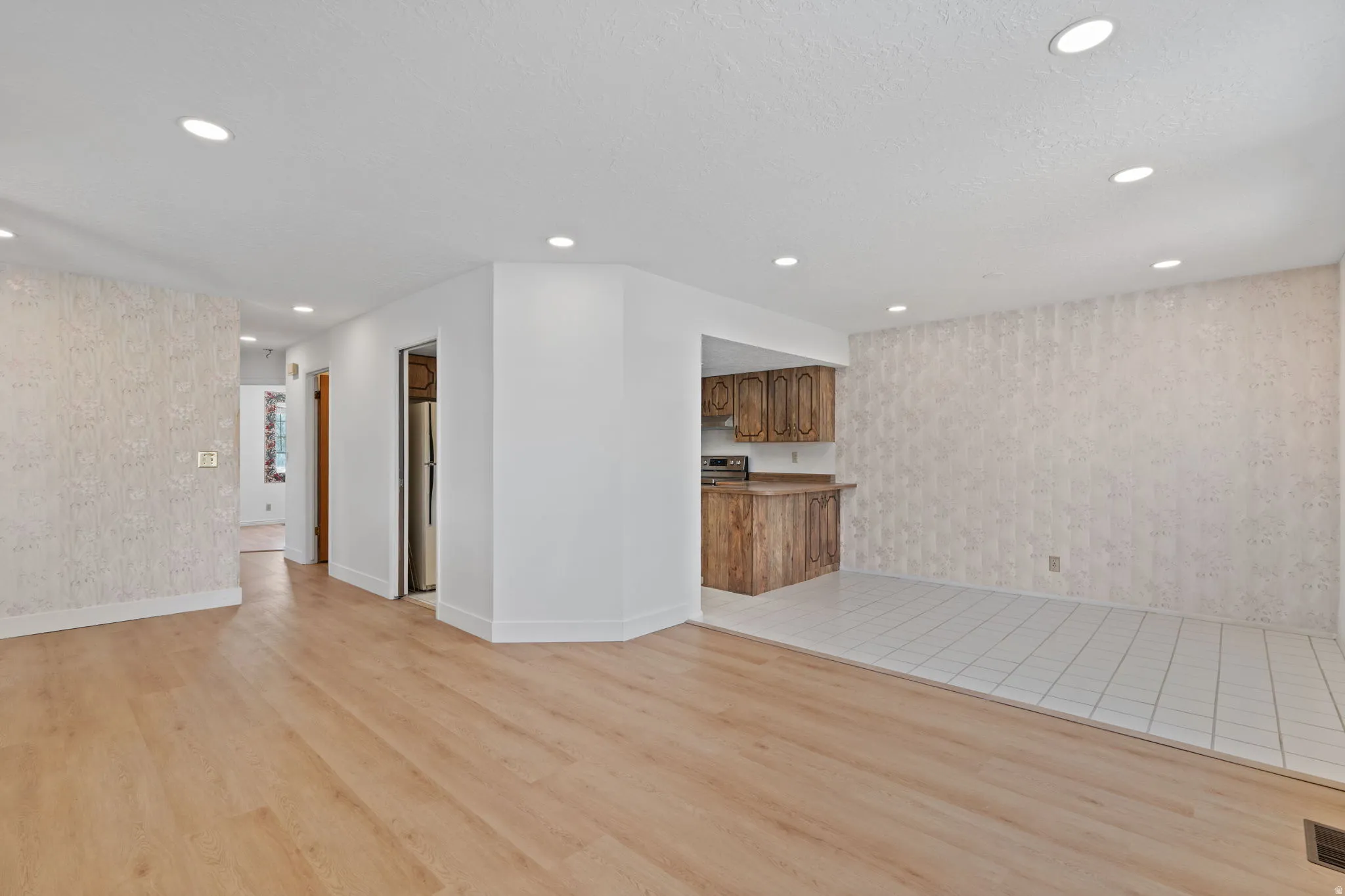 Open-concept living area with wood-finish flooring, recessed lighting, and a distinct tiled section