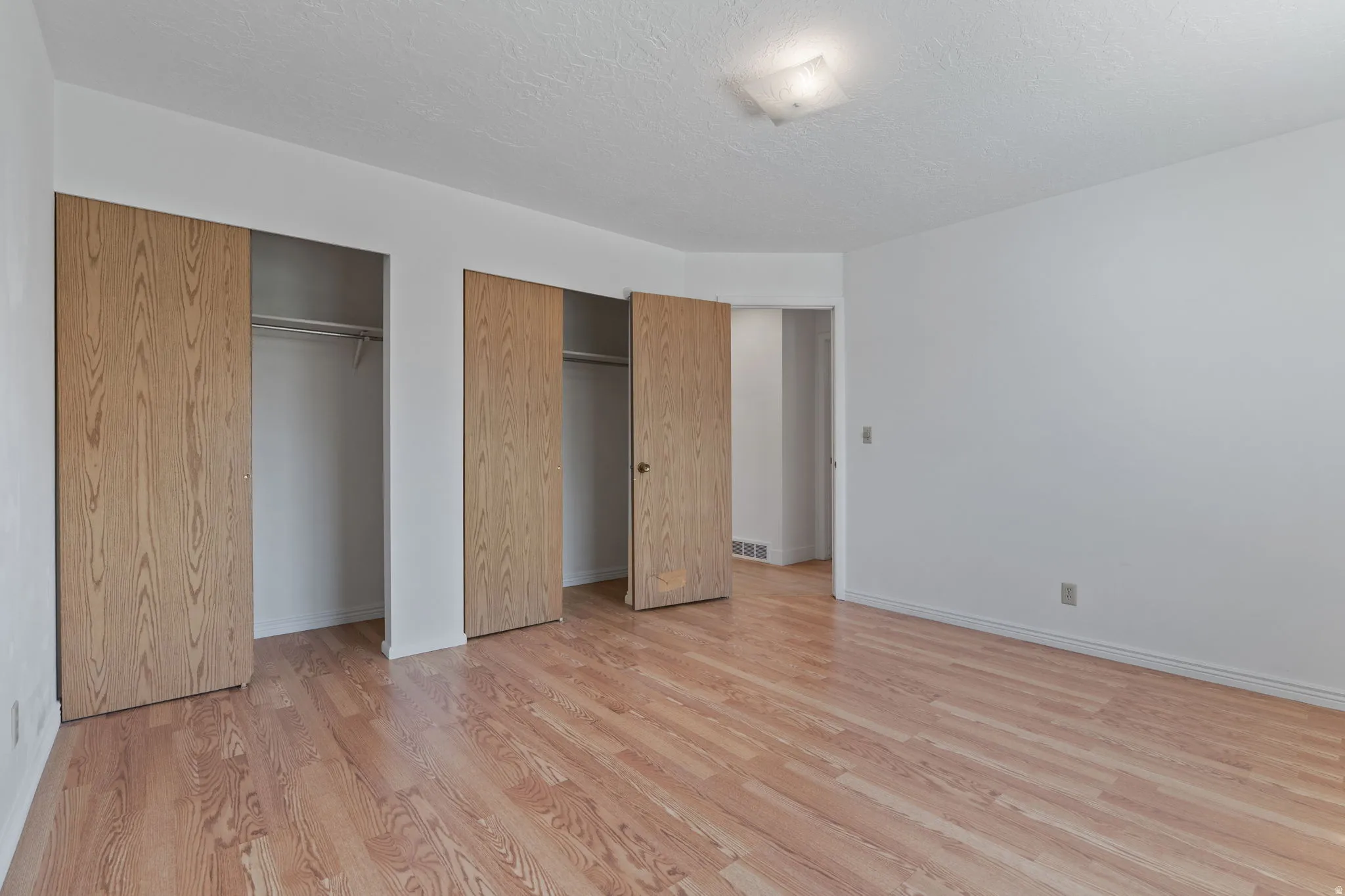 Wood-finish flooring throughout, multiple bi-fold closet doors, and recessed ceiling lighting