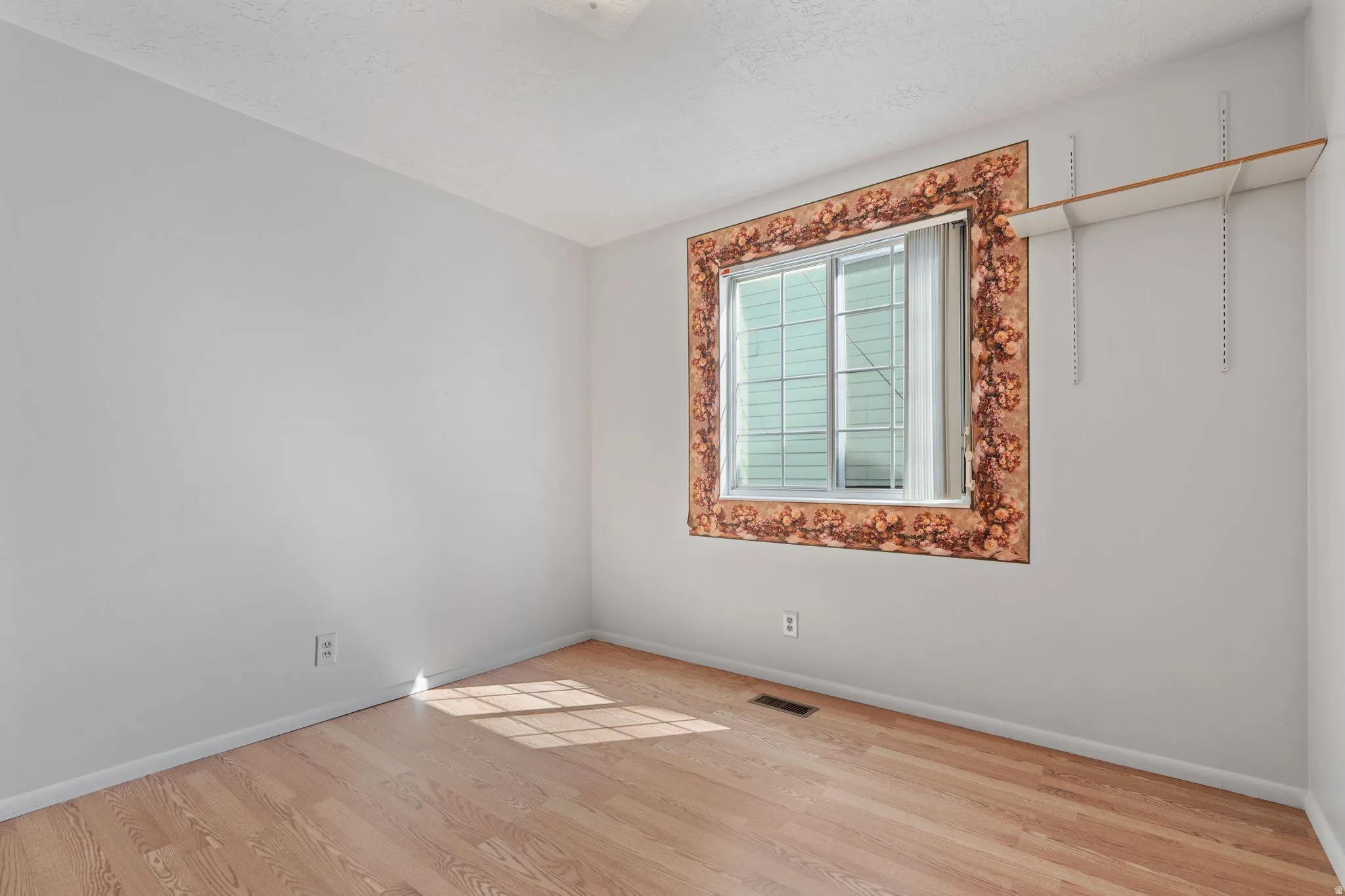 Wood-finish flooring, white walls, and a window with a decorative border