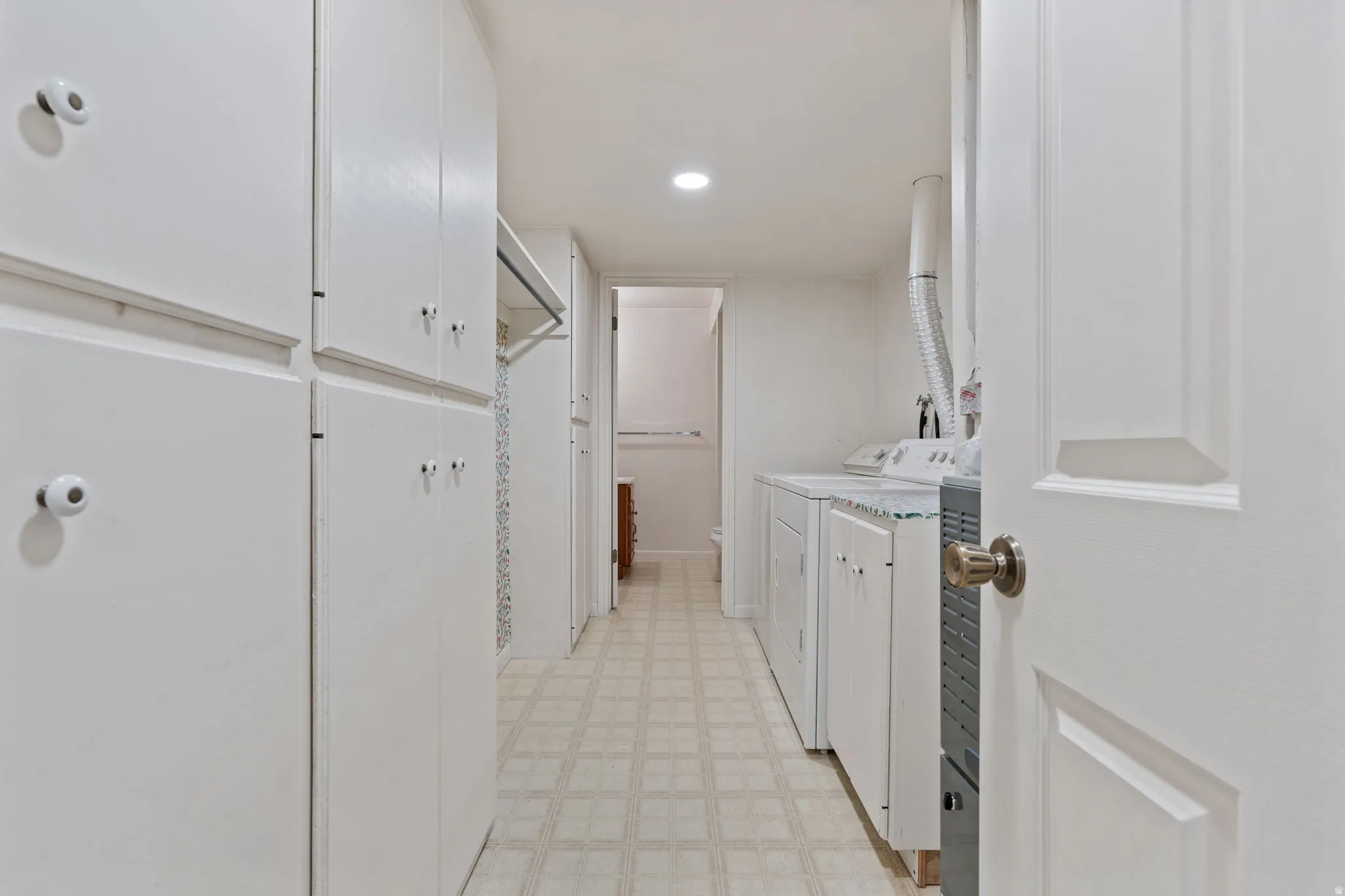 Built-in white cabinetry, recessed lighting, and a washer and dryer