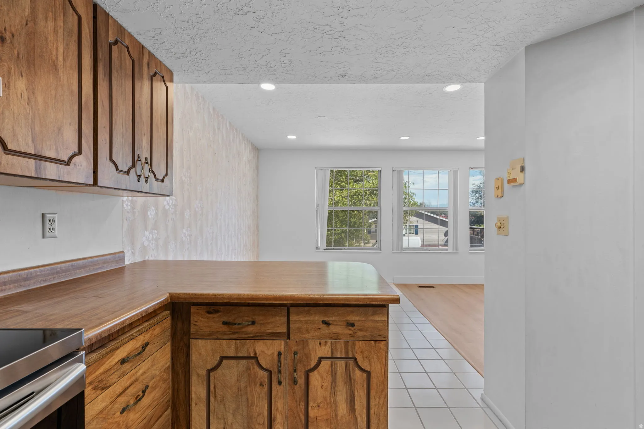 Wood-finish cabinetry and countertops, recessed lighting, and white tile flooring