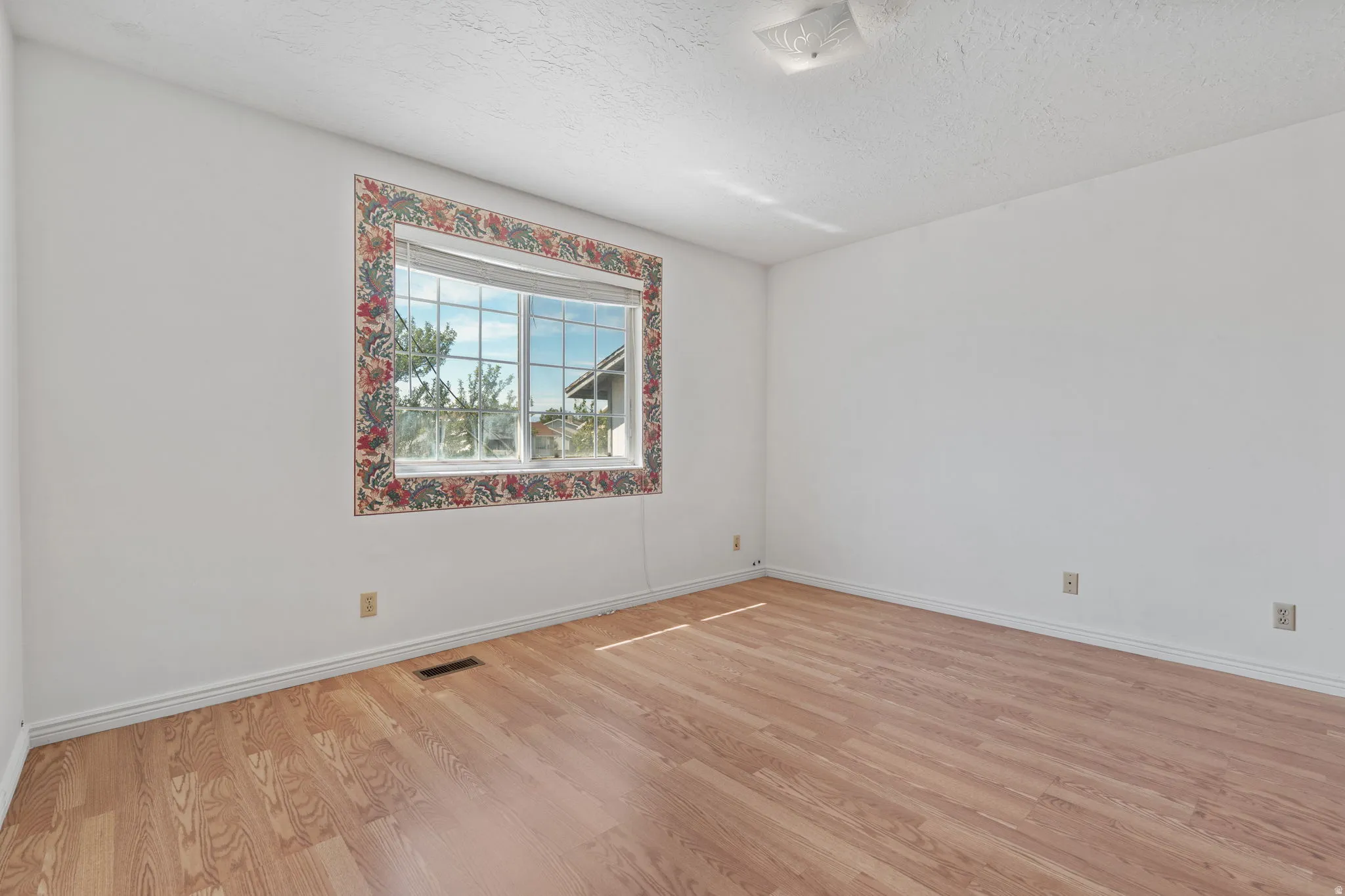Wood-finish flooring with white walls and a large window