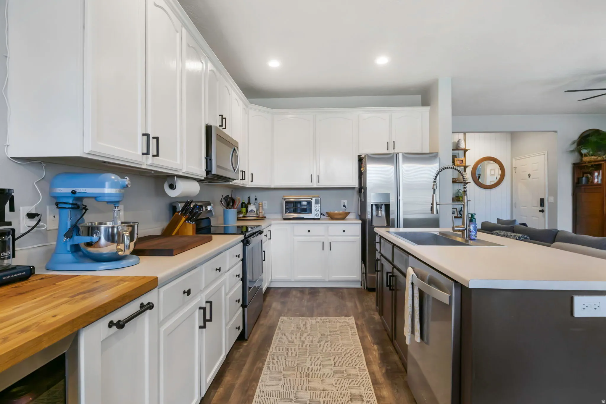 Kitchen featuring white upper and lower cabinetry, stainless steel appliances, and a large island with an undermount sink