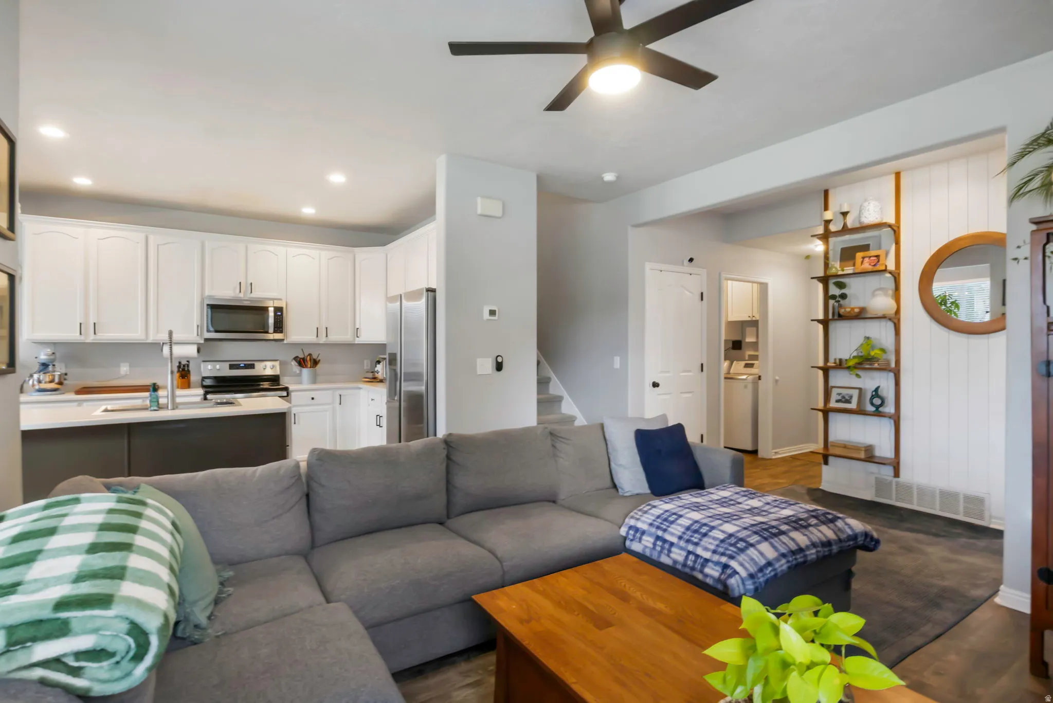 Open-concept living area featuring a ceiling fan, wood-finish flooring, and a kitchen.