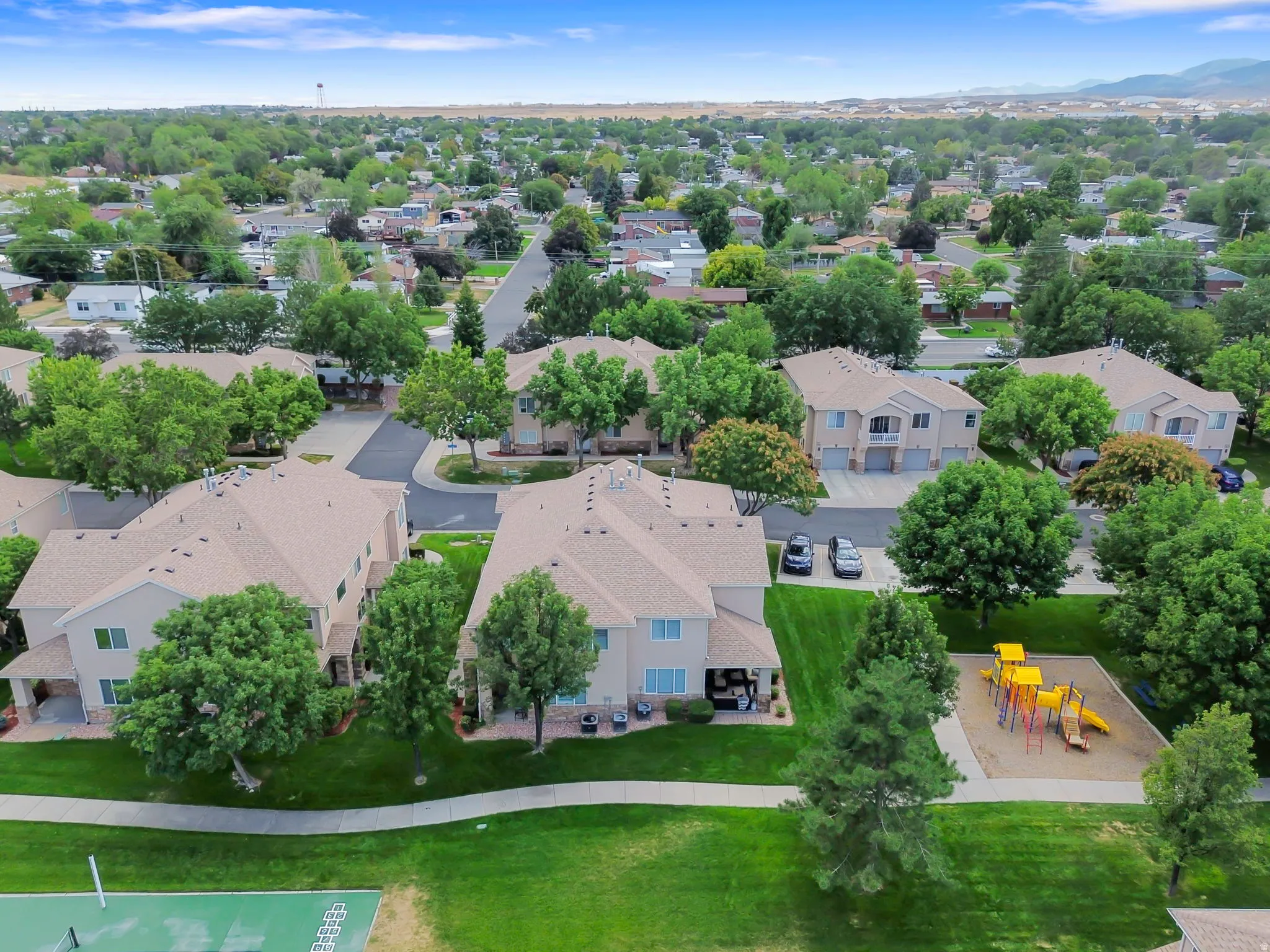 Residential community with multi-story buildings, surrounding green spaces, and mature trees