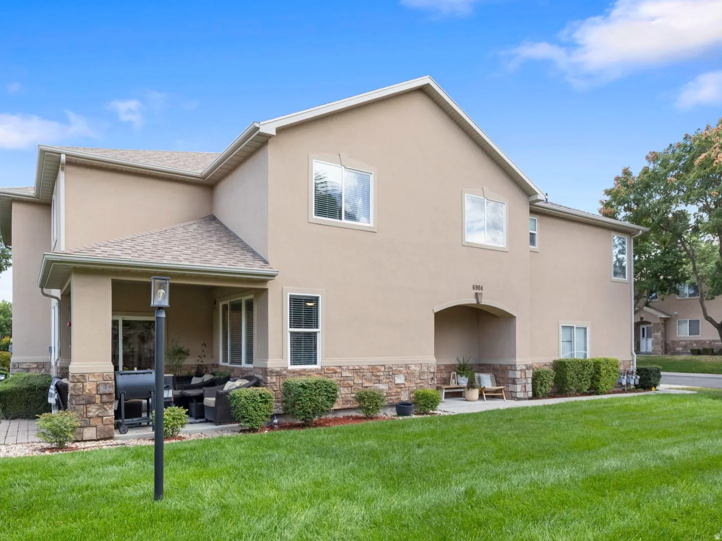 Stucco exterior with stone veneer accents, and covered patio