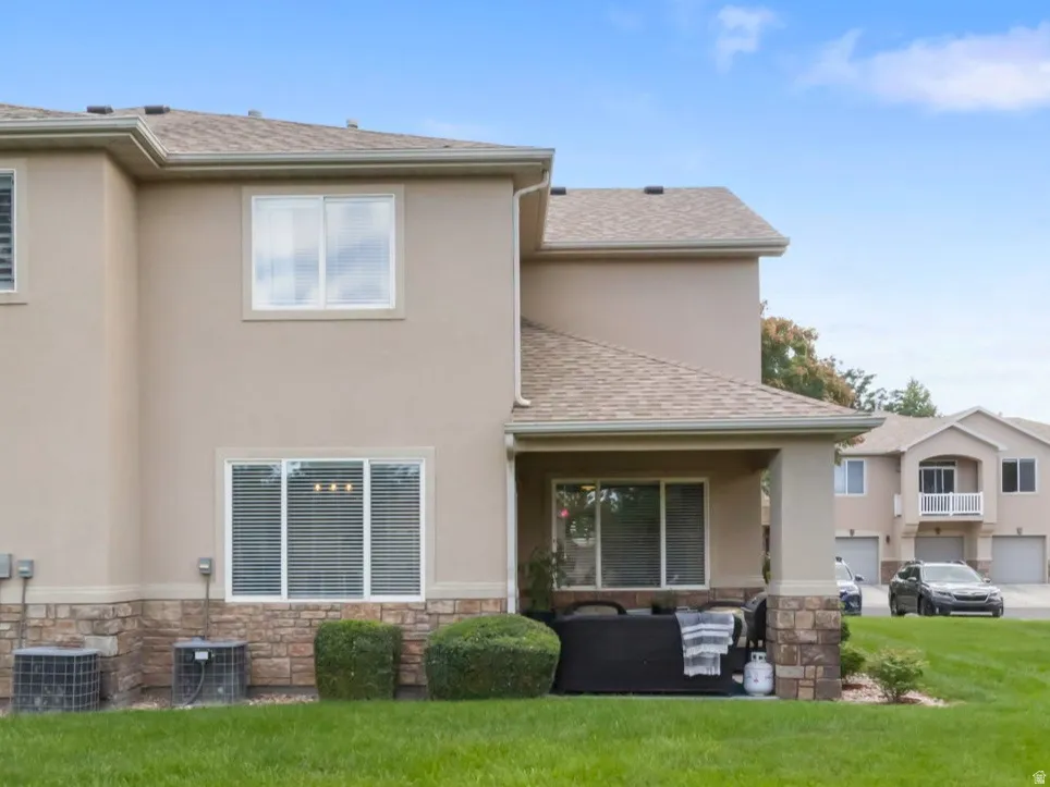 Stucco exterior with stone veneer accents, multiple windows and a covered patio