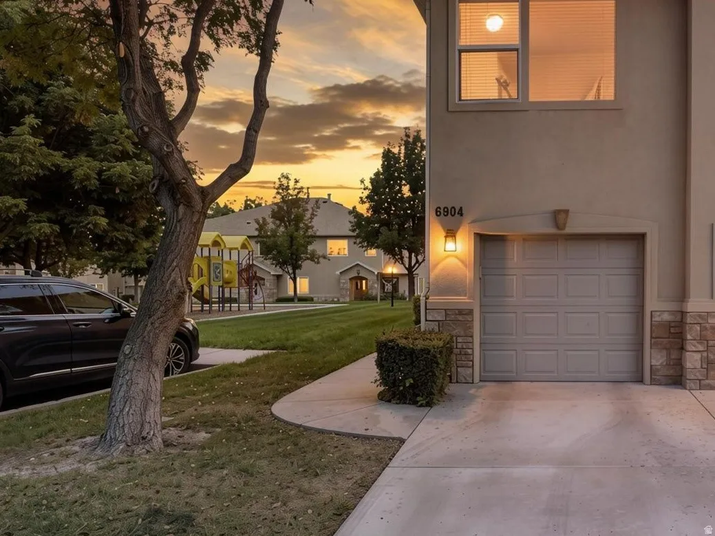 Modern condo featuring one car garage, driveway, and mature landscaping with established trees
